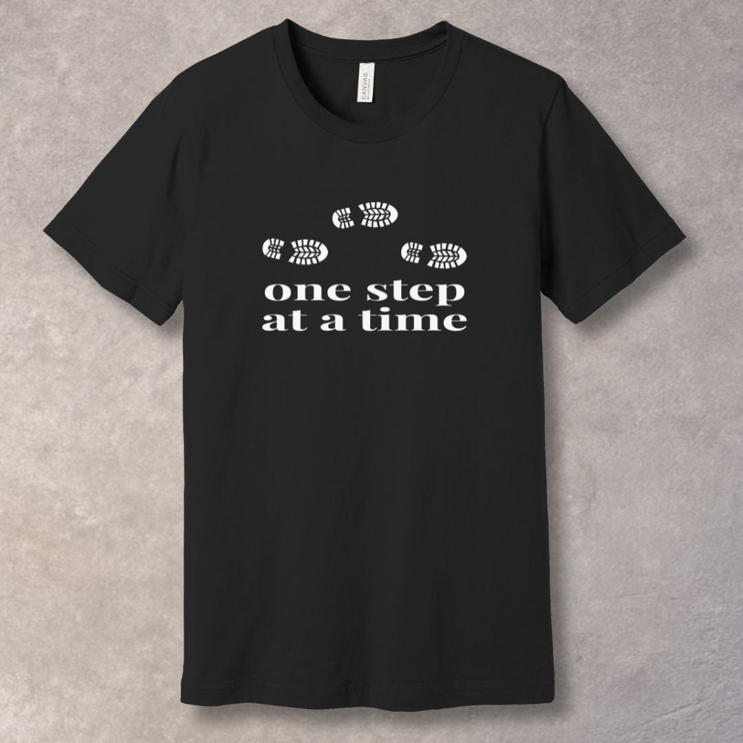 Black t-shirt with 'one step at a time' text and footprints design