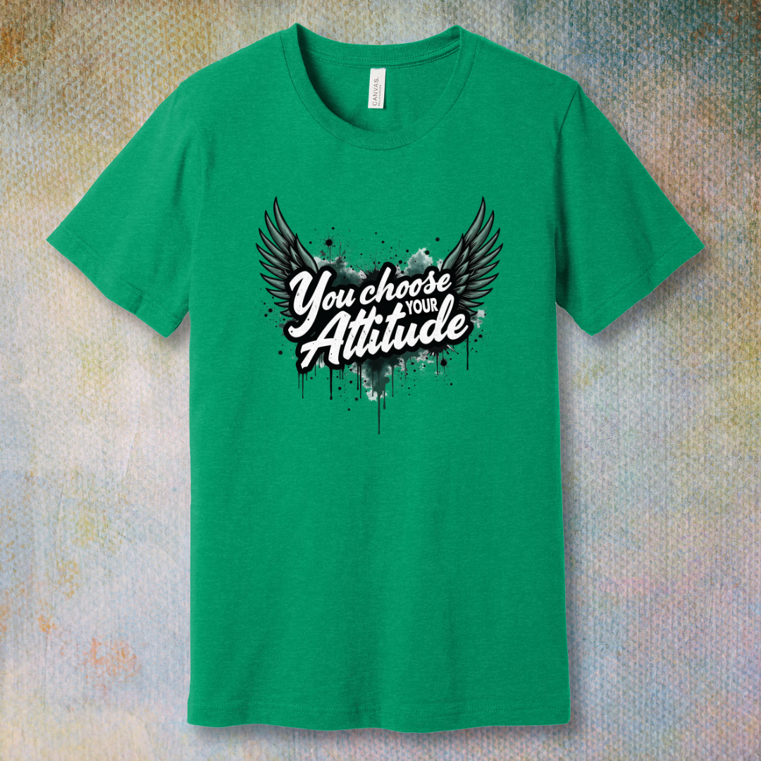 Heather Kelly motivational T-shirt with “You Choose Your Attitude” text and black wings graphic over ink-splatter background
