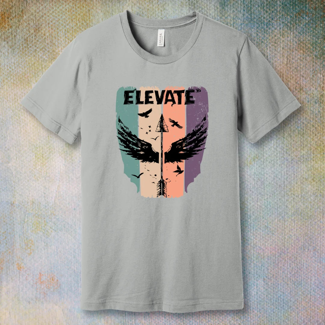 Silver t-shirt with artistic design with an arrow with wings pointing up and the word "Elevate" in bold, symbolizing growth, positivity, and inner power