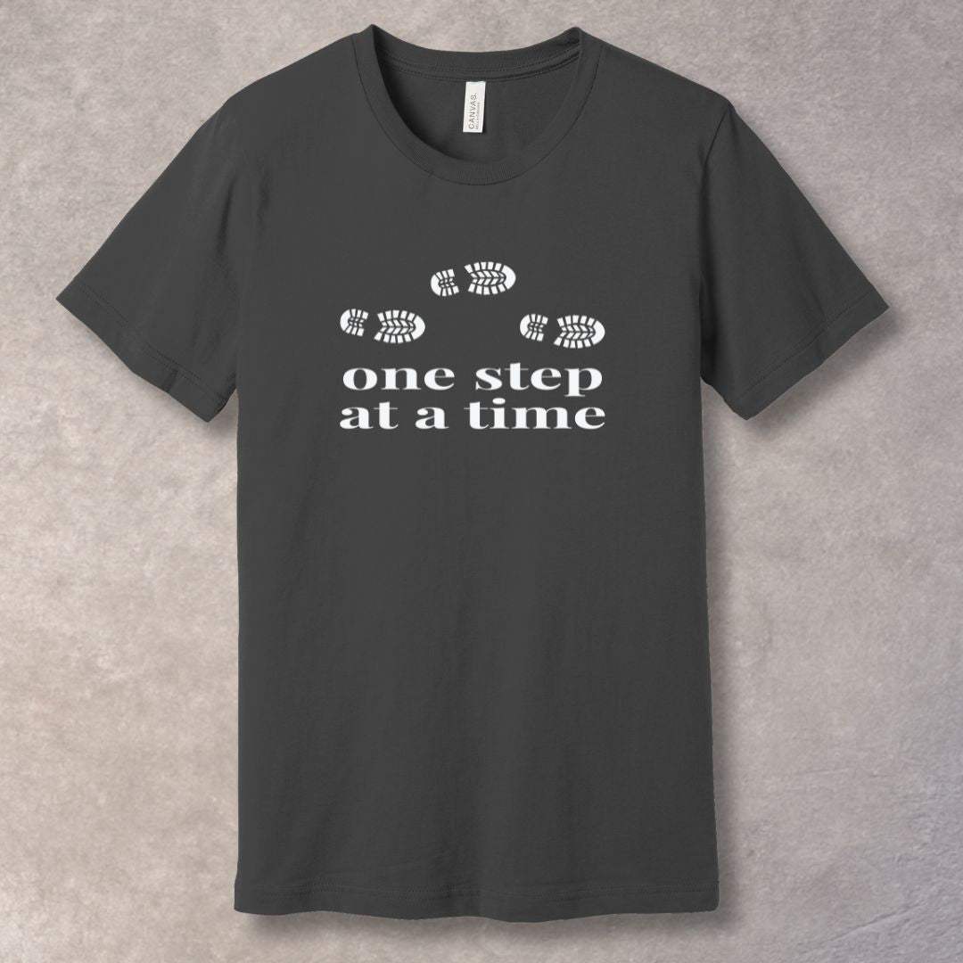 Gray t-shirt with 'one step at a time' text and footprints design