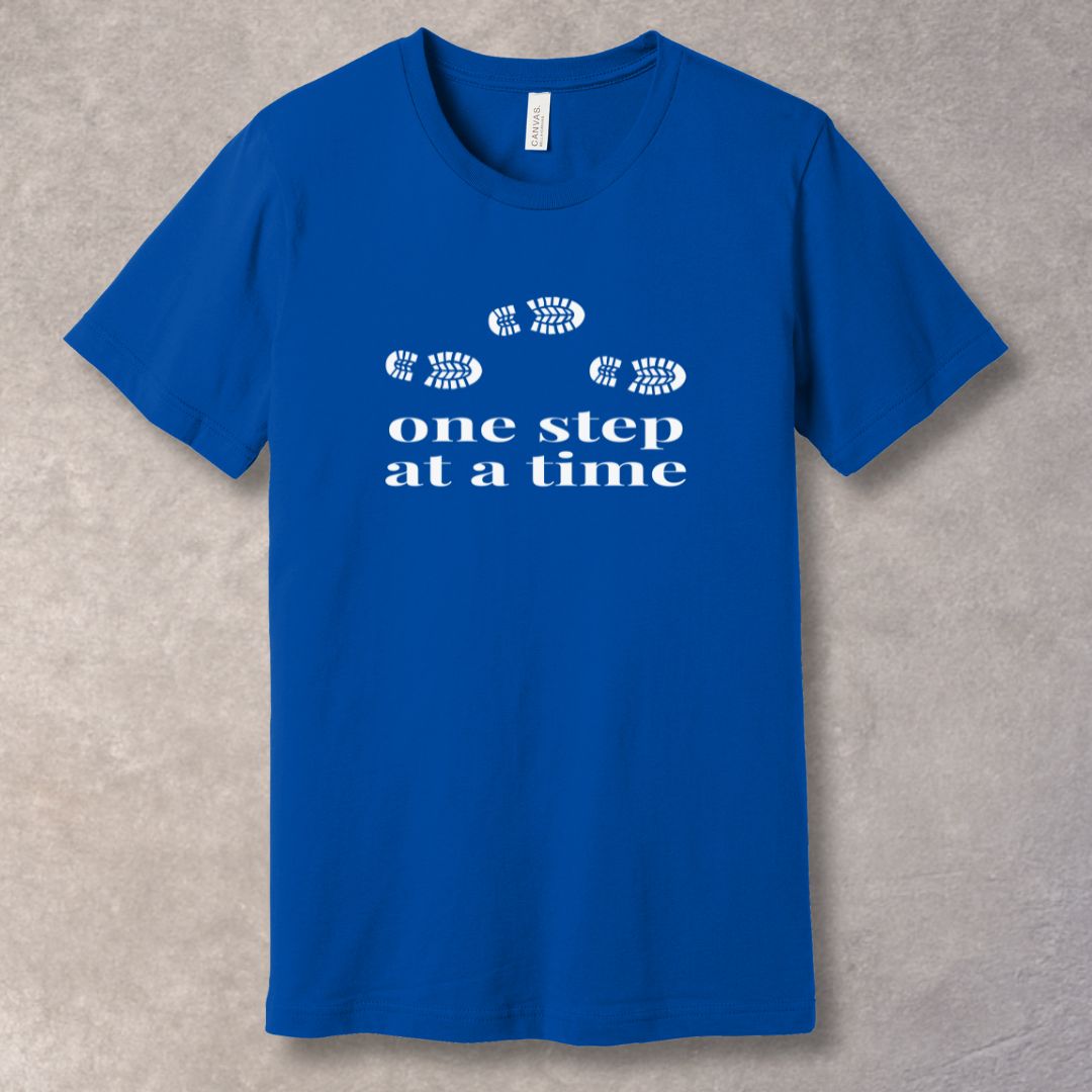 Blue t-shirt with 'one step at a time' text and footprints design