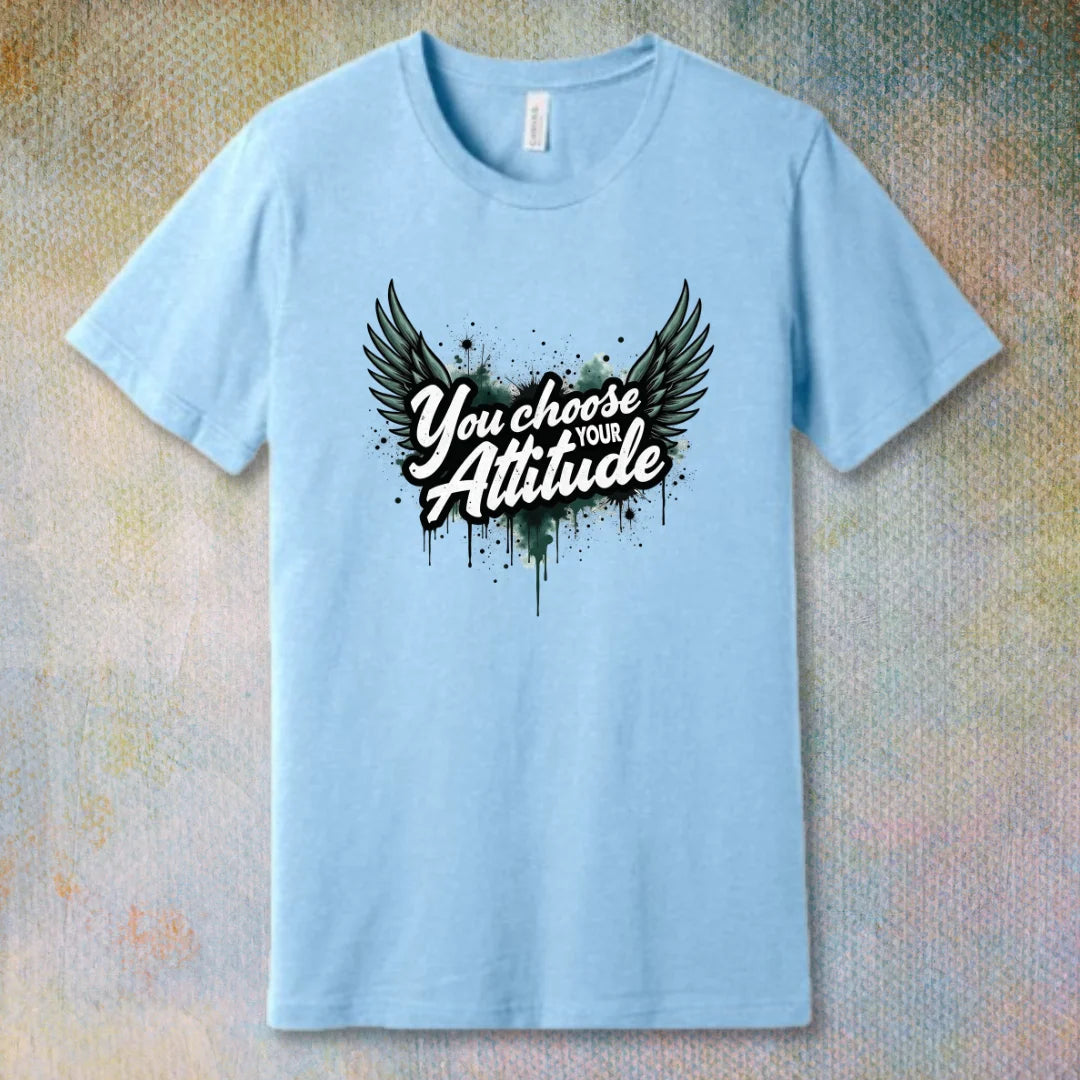Baby Blue motivational T-shirt with “You Choose Your Attitude” text and black wings graphic over ink-splatter background